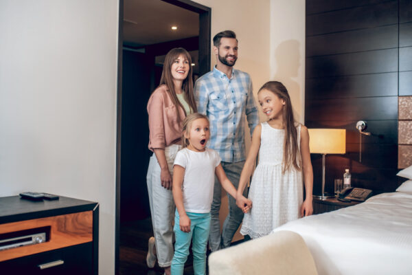 Familie cu doi copii intrând într-o cameră de hotel