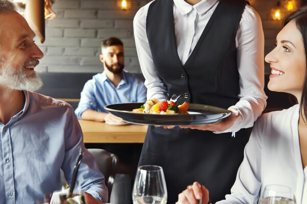 Chelneriță servește mâncare unui cuplu la restaurant