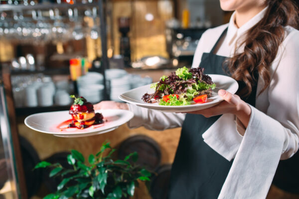 Chelneriță servește salată și desert în restaurant