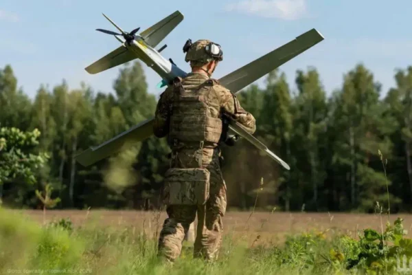 Soldat transportând dronă militară pe câmp