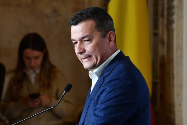 Bărbat în costum susținând discurs la pupitru