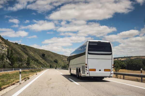 Autocar alb pe autostradă printre dealuri verzi