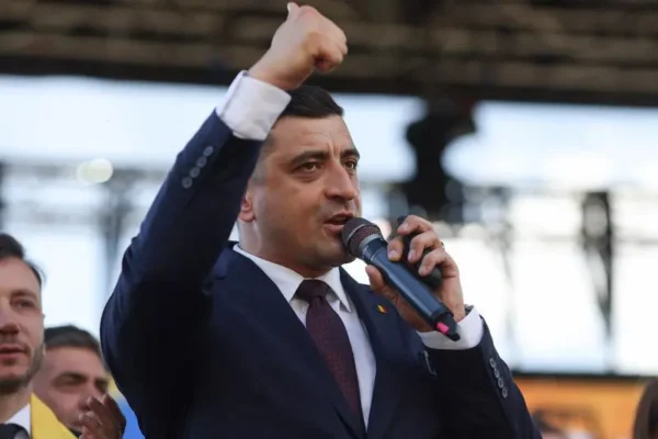Bărbat în costum vorbește la microfon, ridicând pumnul
