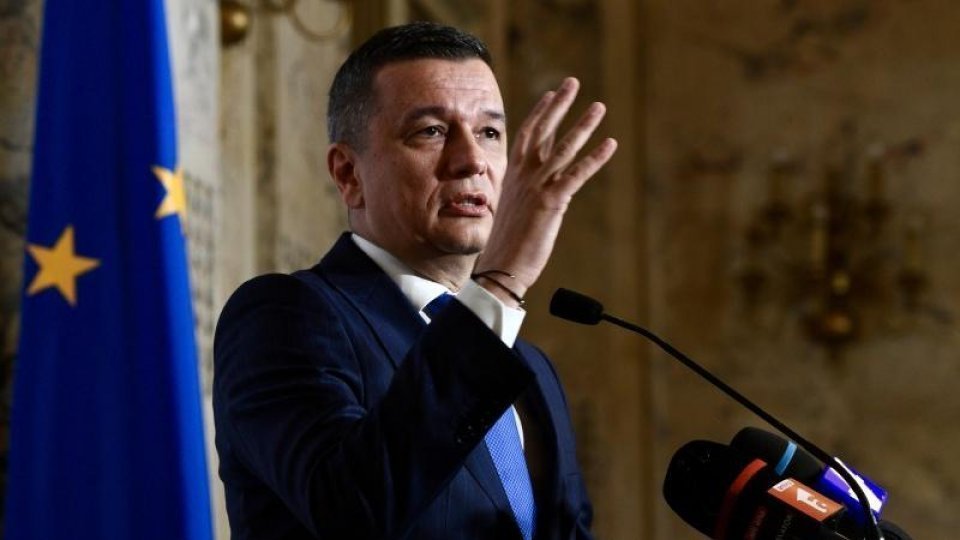 Bărbat la pupitru vorbind, steagul UE în fundal